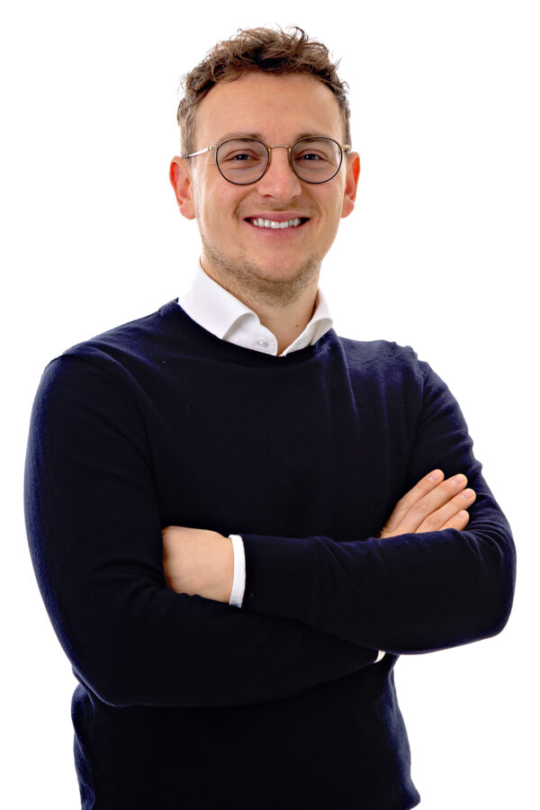 Lijsttrekker Kevin Bax staat met zijn armen over elkaar en kijkt lachend