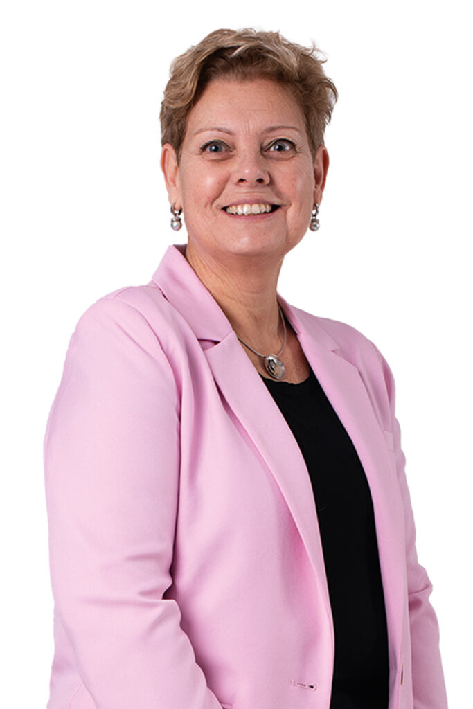 Carla Dieteren kijkt je lachend aan. Ze draagt een zwart shirt en een lichtroze colbert.