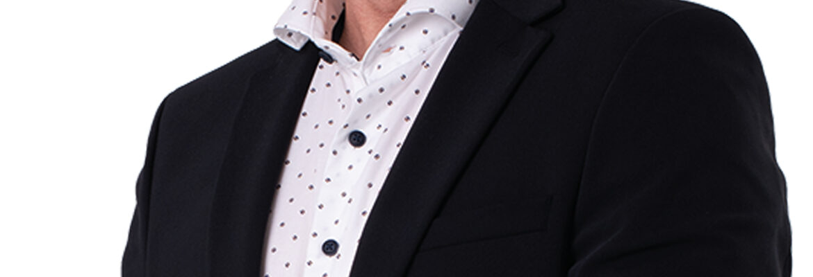 Jan-Willem van Gog kijkt je lachend aan. Hij draagt een wit overhemd en een donkerkleurig colbert